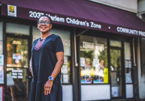 Woman stands smiling in front of Harlem Children's Zone office