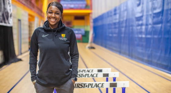 Female track coach smiling and standing in front of track equipment