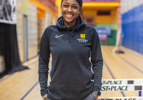 Female track coach smiling and standing in front of track equipment