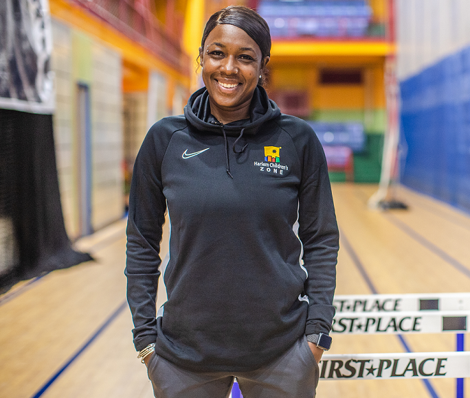 Female track coach smiling and standing in front of track equipment