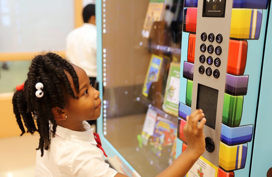 An HCZ Promise Academy Elementary School scholar uses her token at the book vending machine.