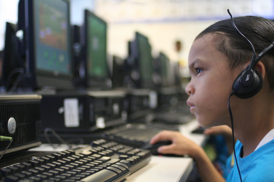 A young boy is working at a computer with headphones on