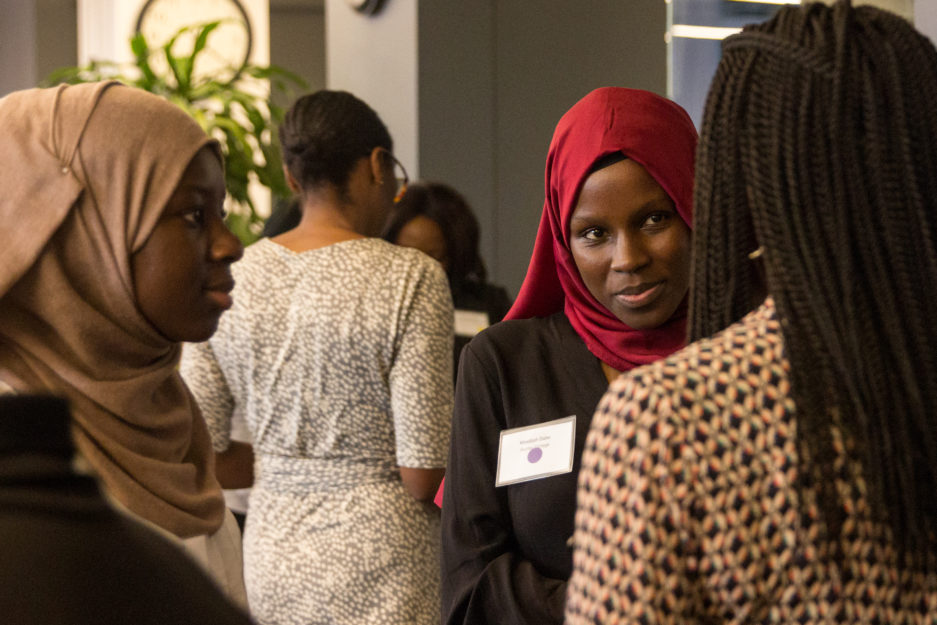 youth programs | Two female college students speak to a woman about her career at a college career networking event