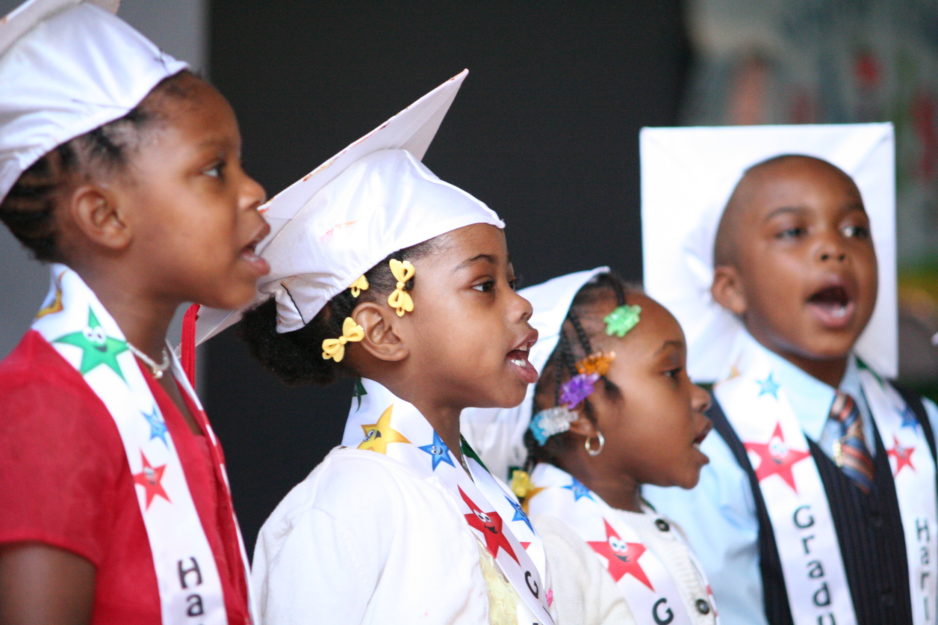 HCZ | Four preschool graduates sing in their cap and gowns at their graduation ceremony.