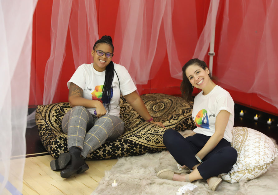 Two adult women smile while sitting on floor pillows