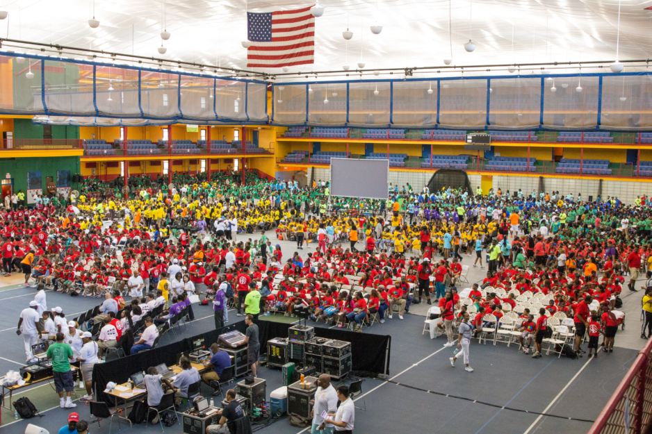A large group of people in colorful matching shirts gathered in a sports dome
