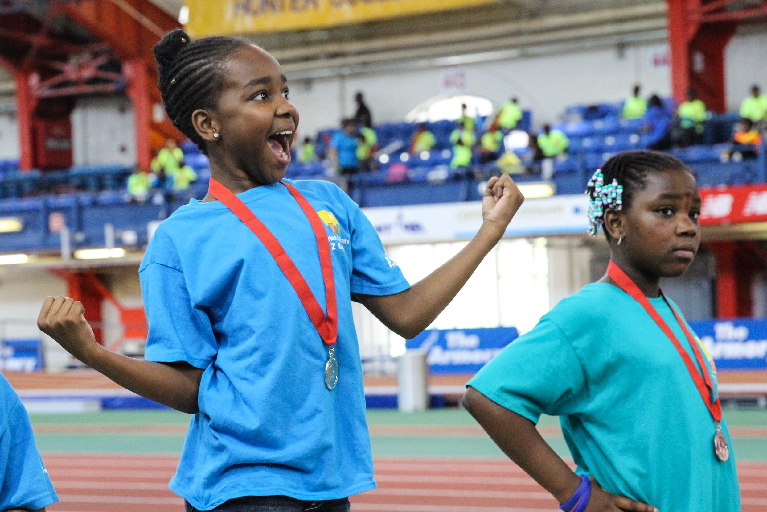 Young girl smiling with medal on track.