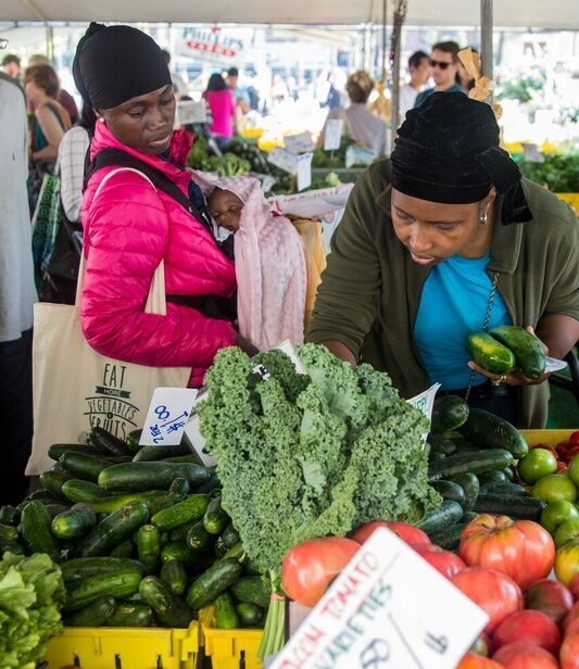 Two women shoppers browse produce at a greenmarket