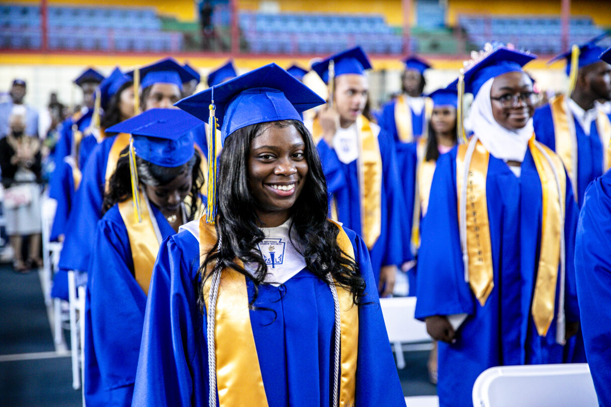 HCZ Promise Academy High School senior smiling in blue robe at graduation.