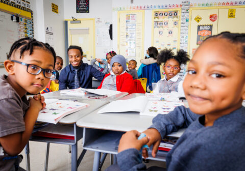 HCZ Promise Academy Elementary School teacher and scholars smile in a classroom.
