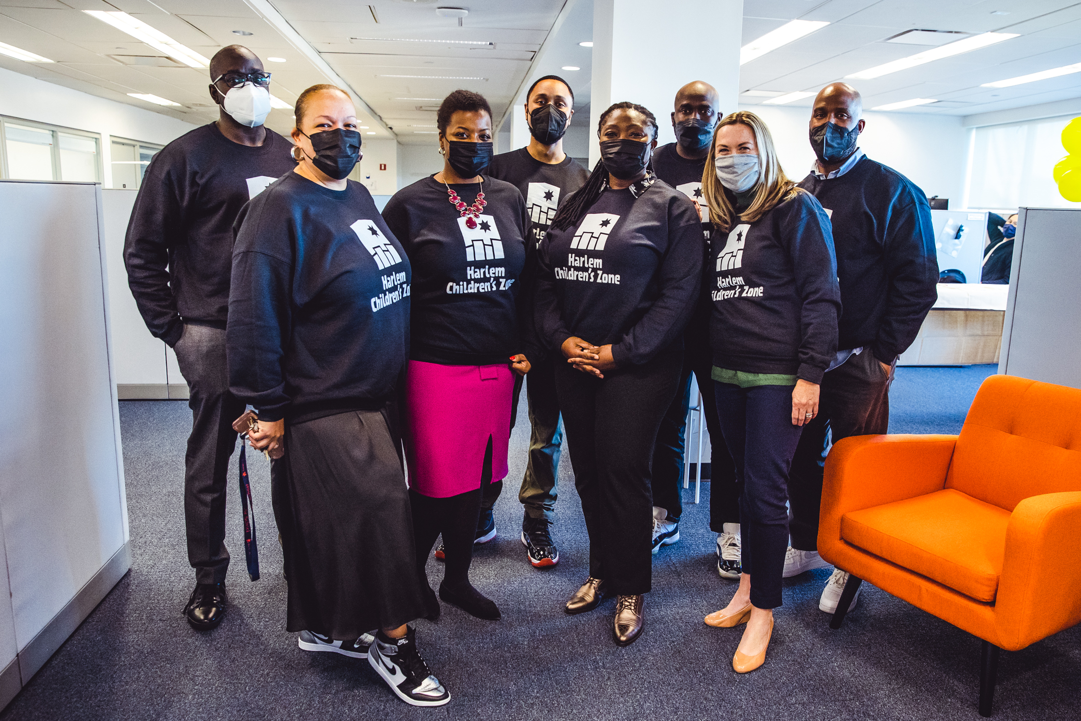 Eight people wearing black Harlem Children's Zone sweatshirts
