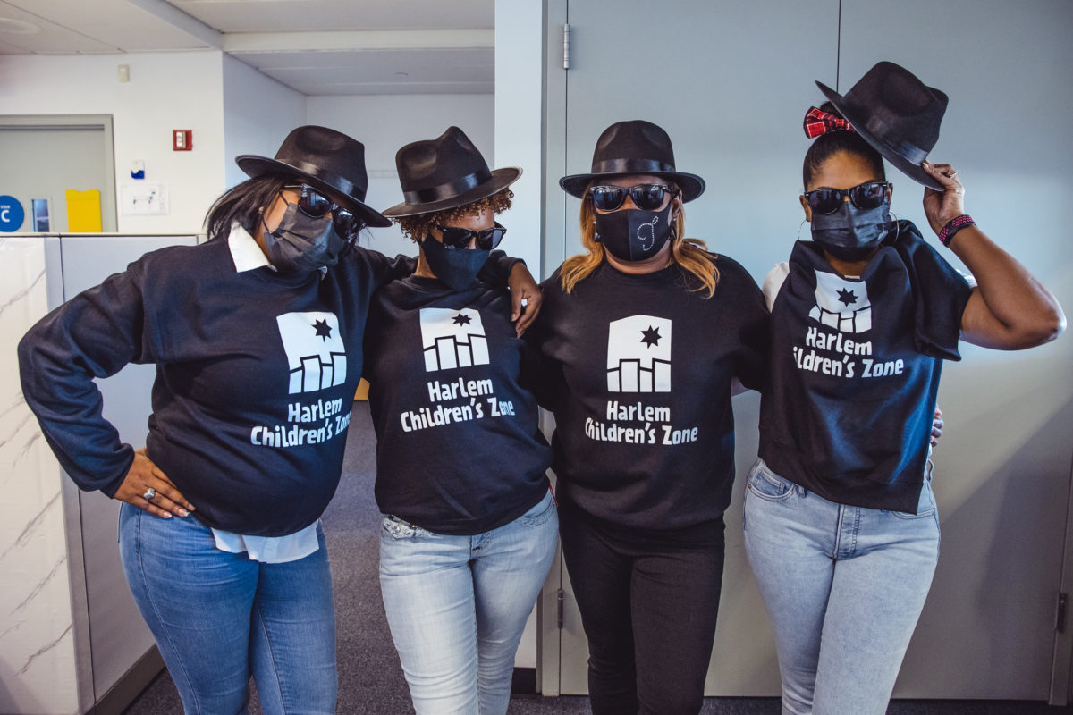 Four women wearing black Harlem Children's Zone sweatshirts and sunglasses