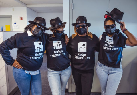 Four women wearing black Harlem Children's Zone sweatshirts and sunglasses