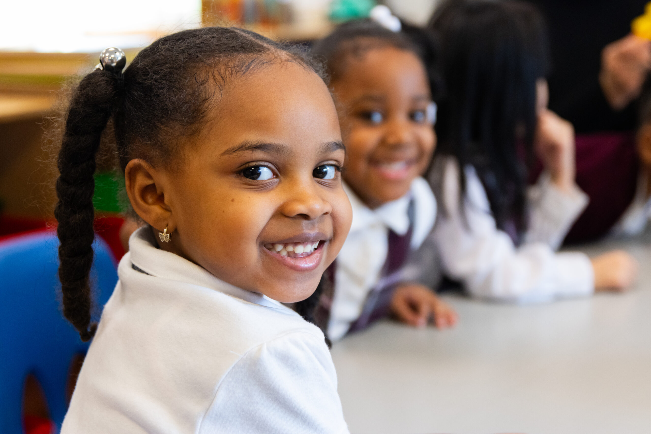 Two young female scholars smile at the camera