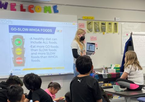 A teacher stands at a whiteboard and presents to her students.