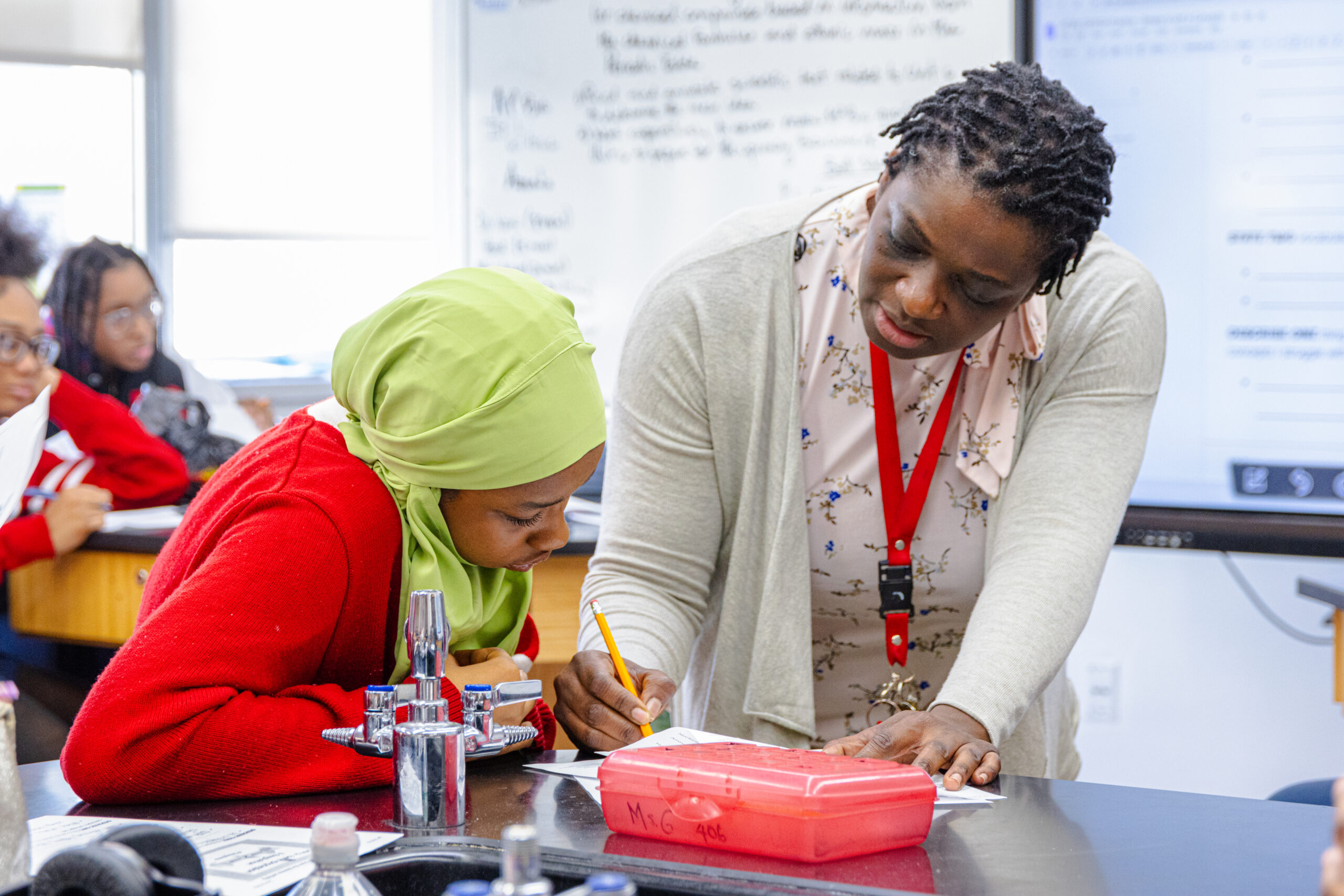 Female teacher helping a female scholar with her classwork.