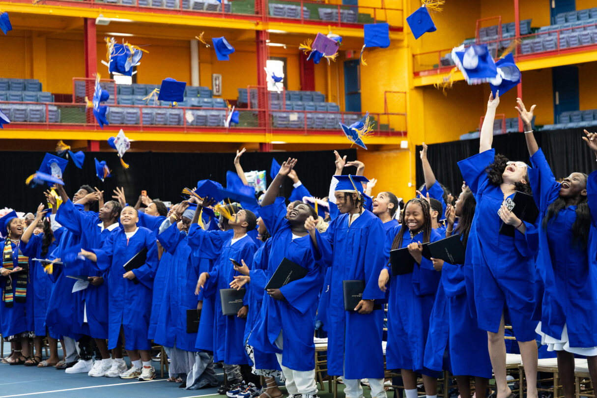 Graduation photo in a gym with scholars in blue cap and gowns