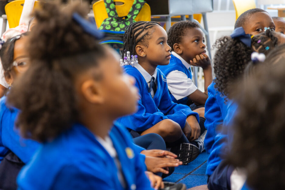 Scholars in blue uniform seated and listening attentively.