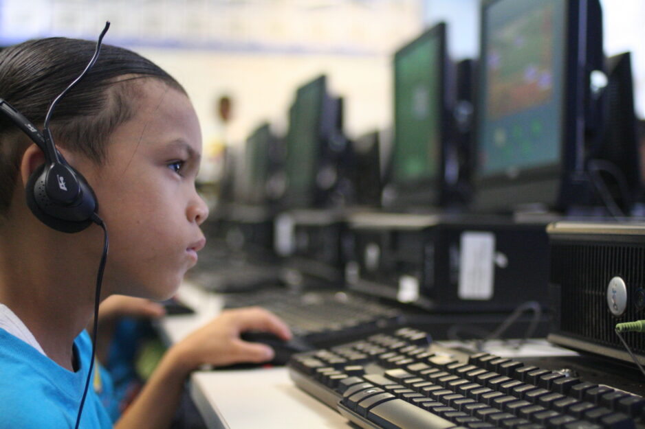 A young boy is working at a computer with headphones on