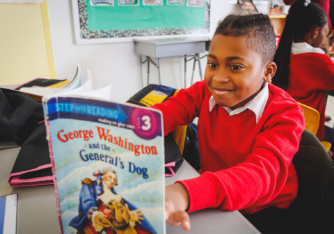 Boy in red sweater reading.