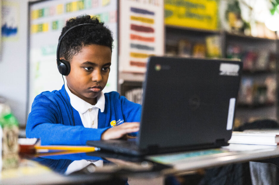 Young male scholar using a laptop at school