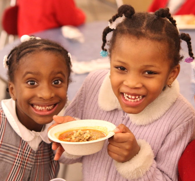 Promise Academy scholars hold a bowl of soup and smile