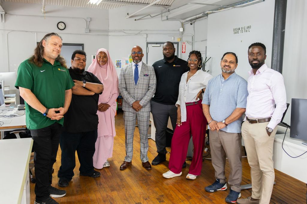 Eight staff members standing up and posing for the camera at their office.