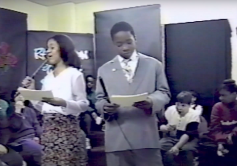 Young Reyna Bonaparte presents a speech with a classmate.