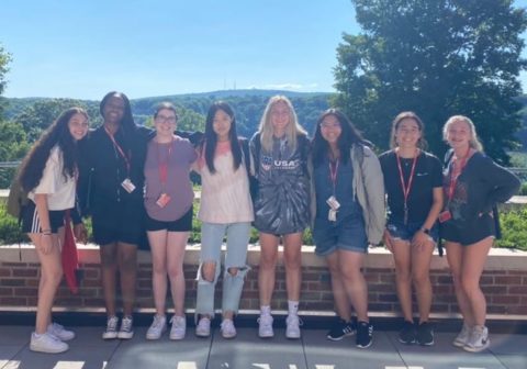 A group of students pose for a photo in front of a scenic view.