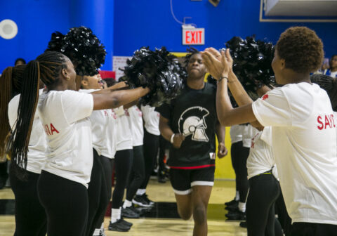 A student athlete walks past a line of cheerleaders.