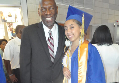 Geoffrey Canada in black suit with Tiffany Gallegos in blue graduation cap and gown.