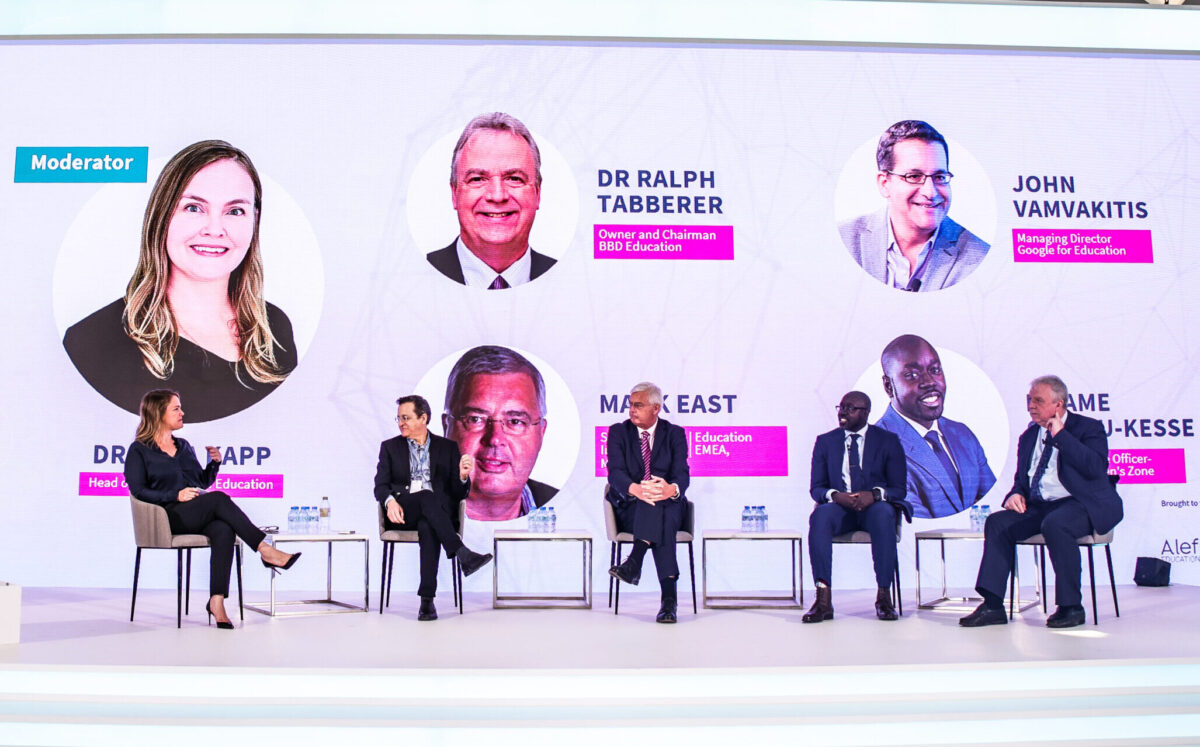 Five people sit on a large stage talking with white background at Alef Education Summit in Dubai, United Arab Emirates.