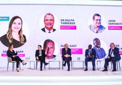 Five people sit on a large stage talking with white background at Alef Education Summit in Dubai, United Arab Emirates.