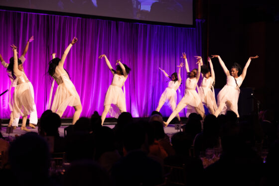 Harlem Children's Zone scholars dressed in white leotards dance on stage at Friend of the Children Award Dinner 2023.