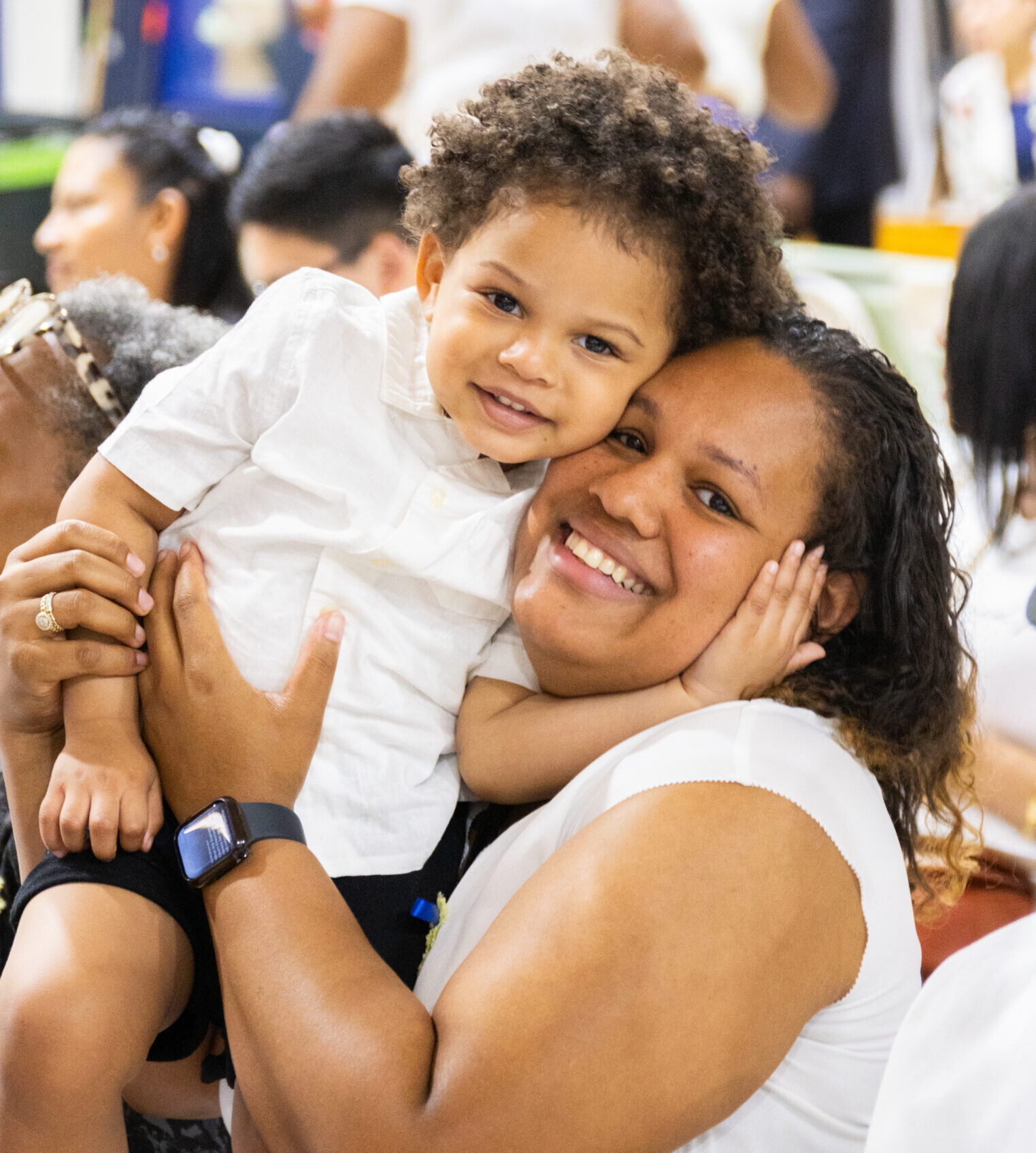 Woman in white sleeveless shirt holds child in white shirt.