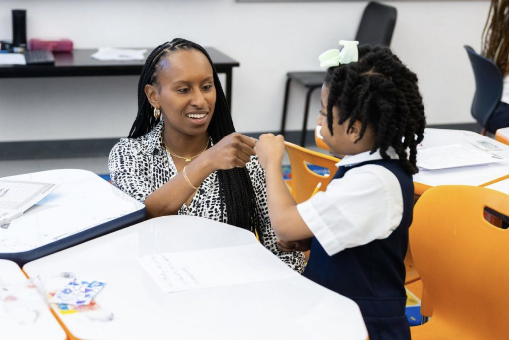 Elementary school teacher Natalia Pierre fist-bumps a young student during a lesson.