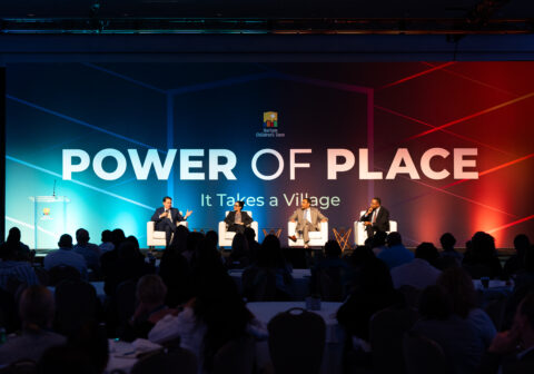 A panel of speakers sit on a stage
