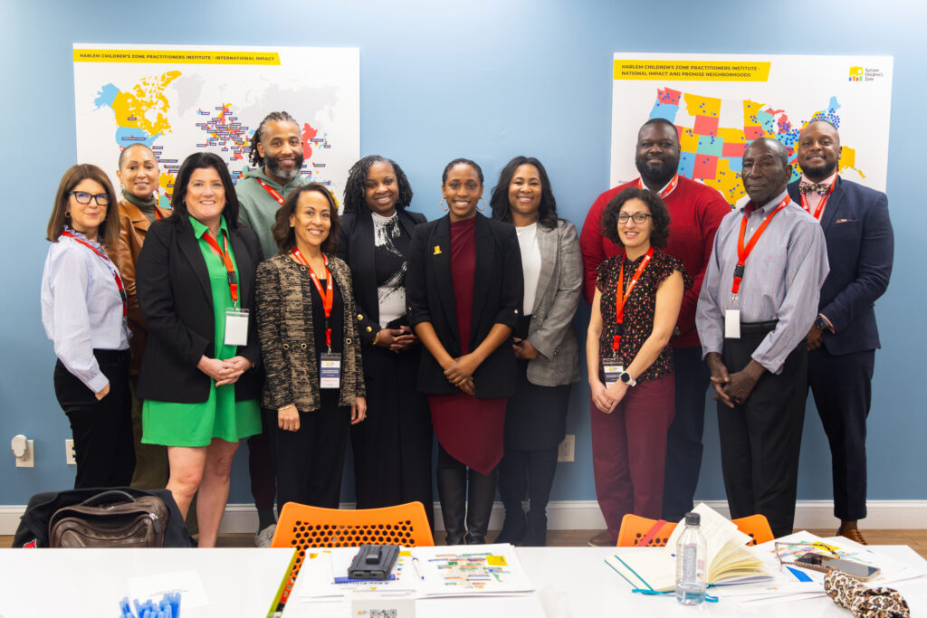 A group of male and female leaders stand and smile at the camera.
