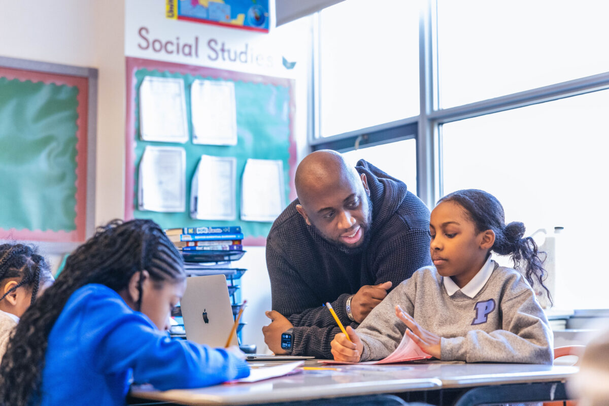 Male teacher helping a scholar with her classwork.