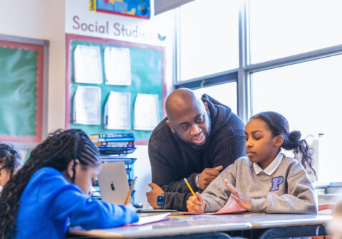 Male teacher helping a scholar with her classwork.