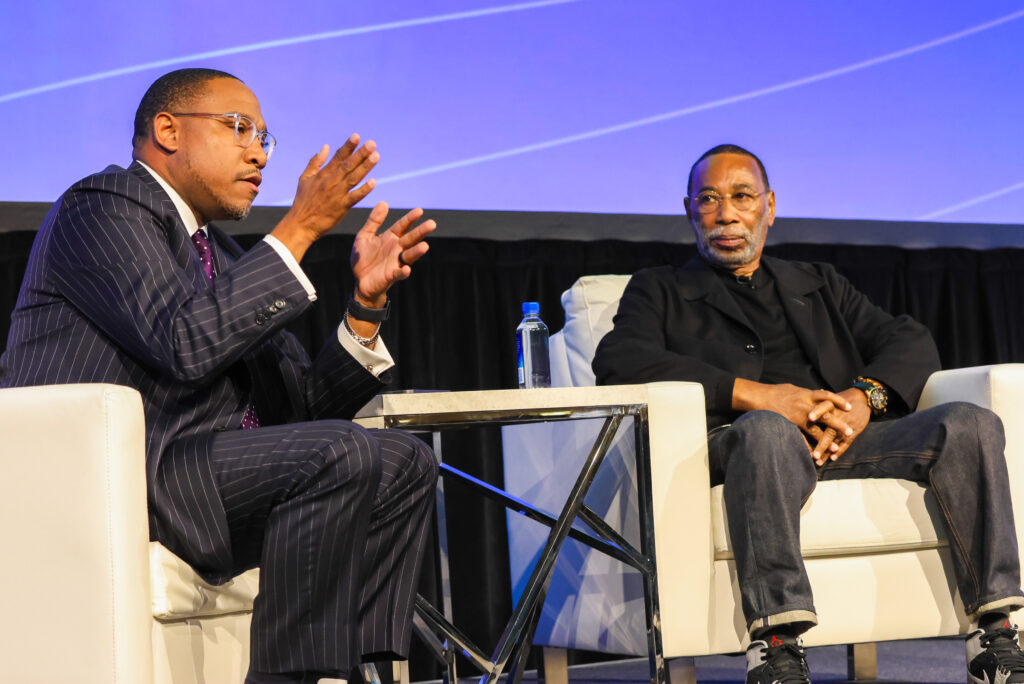 Two men sit on stage having a disucssion