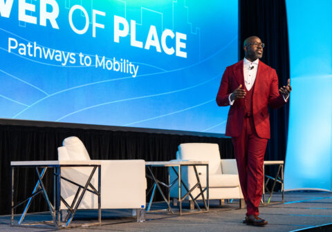 A man in a red suit walks around a stage