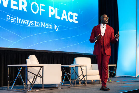 A man in a red suit walks around a stage
