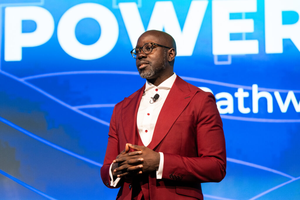 A man in a red suit stands on stage.