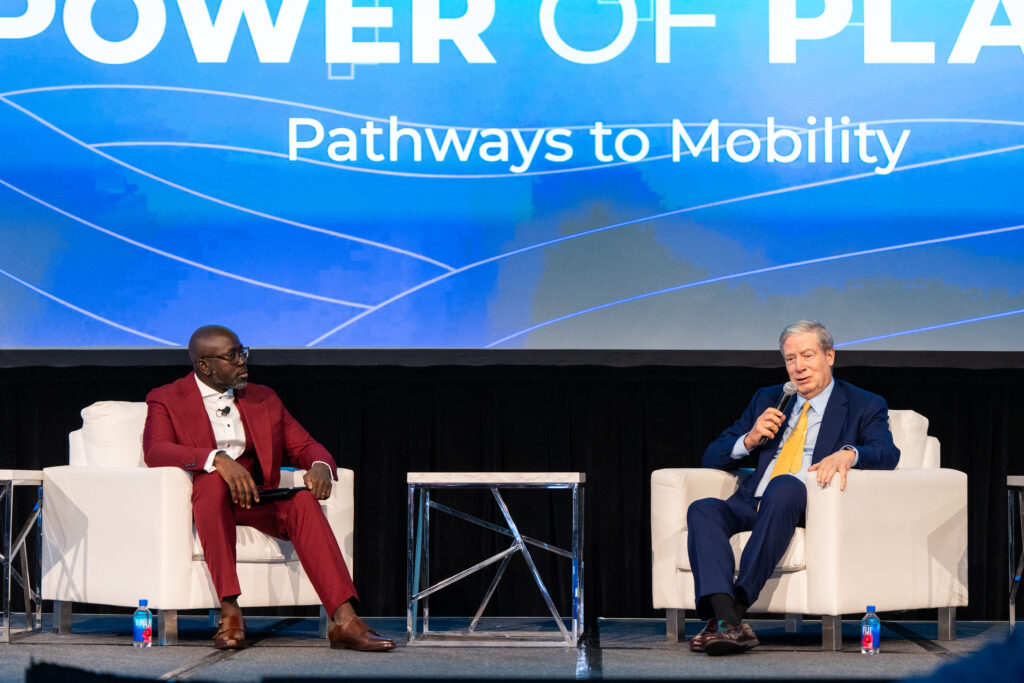 Two men sit on stage having a discussion