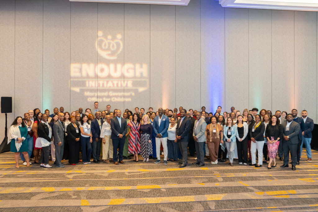 A large group of people stand and smile at the camera