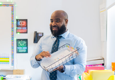 Teachers in classroom holding up paper
