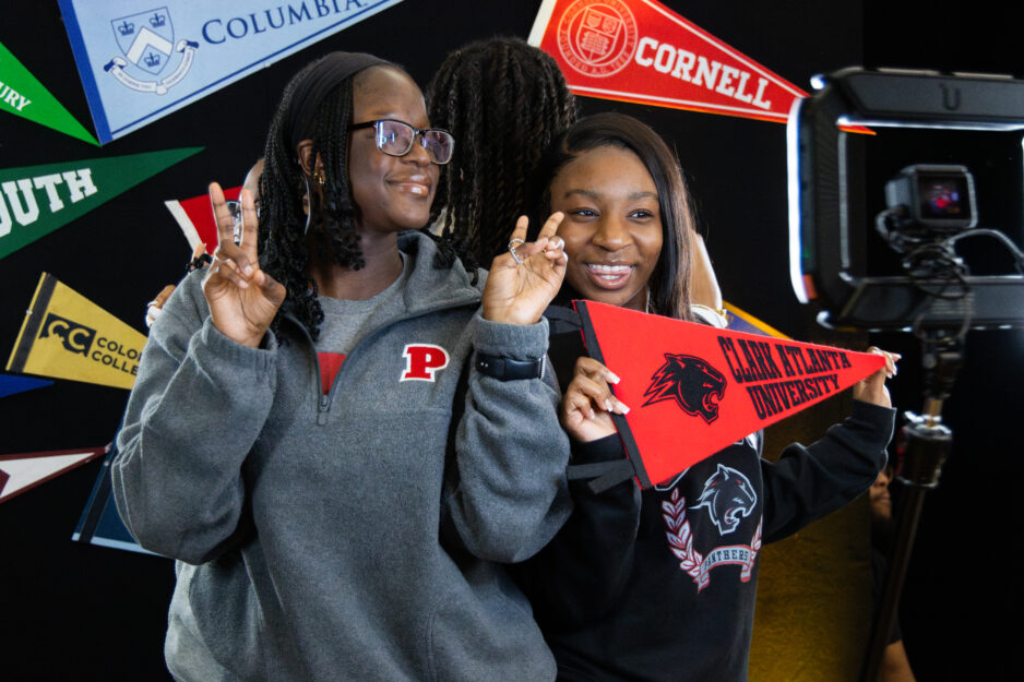 Two female scholars posing with different college memorabilia