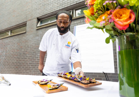Male chef placing food down on a table.