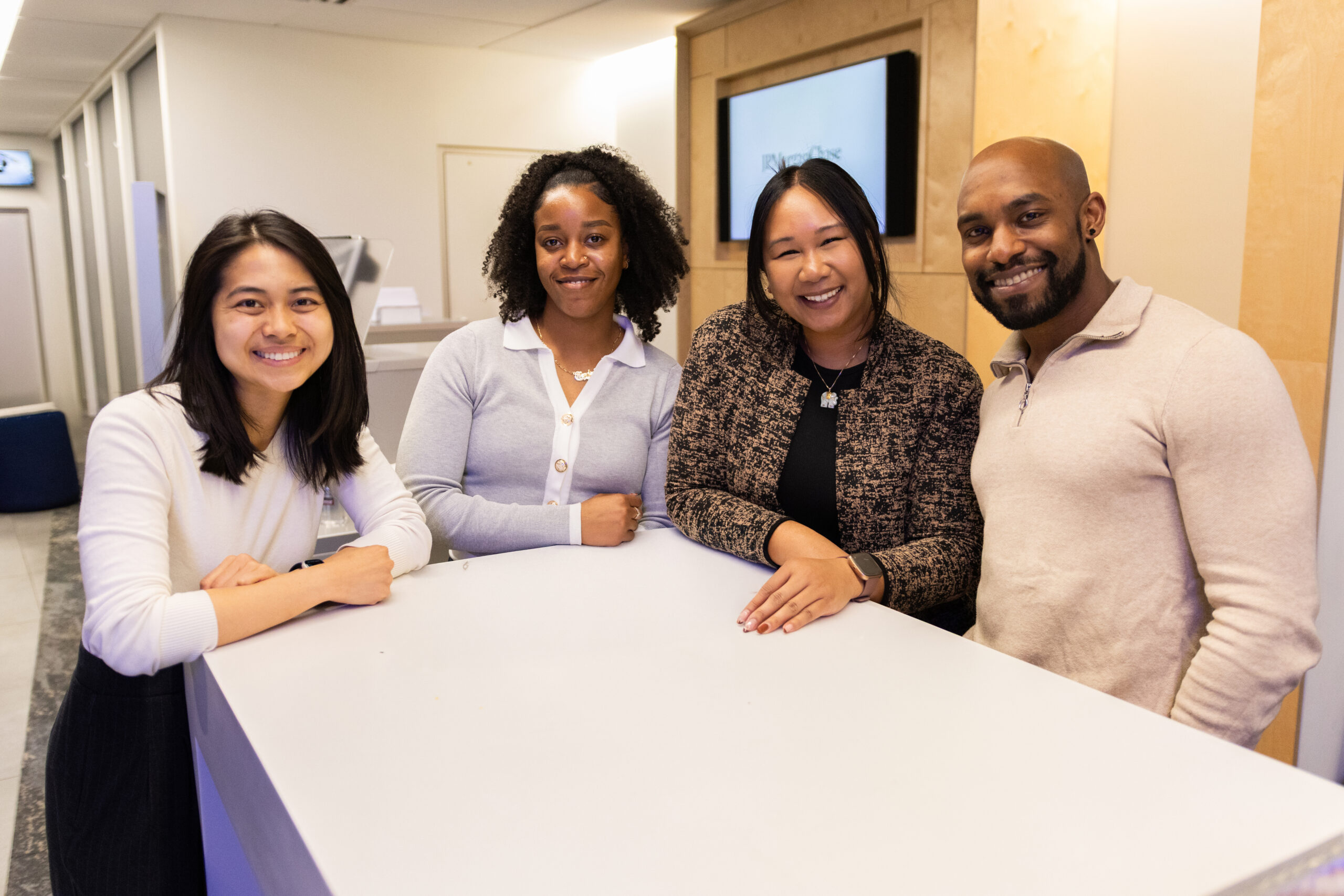 4 staff members standing at a desk smiling for the camera